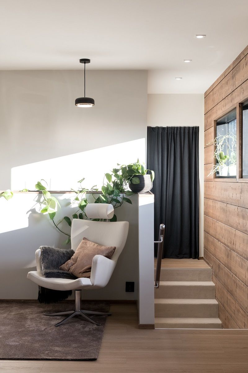 Nell'angolo del soggiorno con illuminazione a sospensione nera e nel corridoio con faretti da incasso